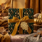 Forest green luxury gift wrap with autumn leaves and a gold velvet bow, by Wrapped Studios.