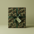 Square gift wrapped in green pine needle Christmas wrapping paper with satin ribbon and gift tag.