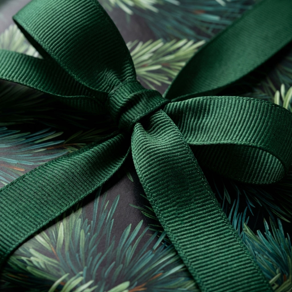 Luxury dark green pine needle Christmas wrapping paper with matching grosgrain ribbon bow. Wrapped Studios.