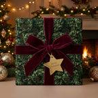 Luxury Christmas gift wrap with evergreen pattern, burgundy velvet bow, and gold tag by Wrapped Studios.
