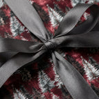 Burgundy Christmas wrapping paper with pine trees, tied with a grey satin bow. Luxury gift wrap by Wrapped Studios.