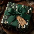 Rustic pine tree Christmas wrapping paper with a green ribbon and Wrapped Studios gift tag.