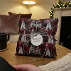 Rustic red Christmas wrapping paper with snowy pine trees and silver string by Wrapped Studios.