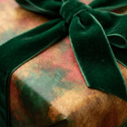 Luxury holiday wrapping paper in a vintage gold and green pattern with a velvet bow, by Wrapped Studios.