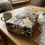 Heart print gift wrapped by Wrapped Studios with twine bow on rustic wood table.