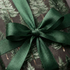 Luxury pine tree Christmas wrapping paper with a dark green satin bow by Wrapped Studios.