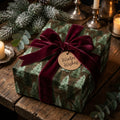 Rustic forest Christmas wrapping paper with a burgundy velvet bow by Wrapped Studios.