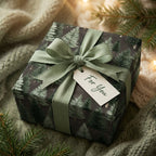 Rustic pine tree Christmas gift wrap with a sage green bow on a cozy gift box by Wrapped Studios.