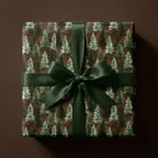 Woodland pine tree Christmas wrapping paper with dark green ribbon, luxury holiday gift wrap by Wrapped Studios.