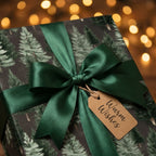 Christmas gift wrap with pine trees, a dark green satin bow, and a Warm Wishes tag by Wrapped Studios.