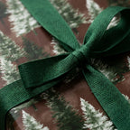 Rustic pine tree Christmas gift wrap with a green herringbone ribbon bow by Wrapped Studios.