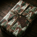 Rustic forest pine tree wrapping paper with a twine bow and leather Dad tag by Wrapped Studios.