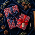 Red plaid Christmas wrapping paper with satin bows on navy velvet, by Wrapped Studios.