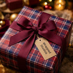 Red plaid Christmas wrapping paper with a burgundy ribbon and tag by Wrapped Studios.