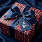Red plaid Christmas wrapping paper with a luxury navy blue ribbon bow and gift tag from Wrapped Studios.