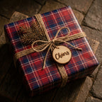 Rustic red plaid Christmas wrapping paper with twine and a wood Cheers tag by Wrapped Studios.