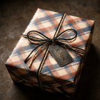 Rustic plaid wrapping paper in navy blue and rust orange with a twine bow by Wrapped Studios.