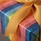 Close-up of a gift wrapped in colorful striped wrapping paper and tied with a gold ribbon.