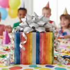 Rainbow striped birthday wrapping paper with a glittery silver bow at a kids' party.