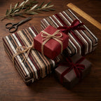Rustic Christmas wrapping paper in brown stripes and solid red with velvet bows by Wrapped Studios.