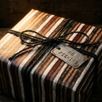 Rustic brown striped wrapping paper with a jute twine bow and No Peeking tag by Wrapped Studios.