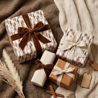 Neutral luxury gift wrap with elegant velvet bows on cozy blankets by Wrapped Studios.