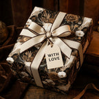 Vintage gothic floral wrapping paper with skulls and cream bow on a gift box, by Wrapped Studios.