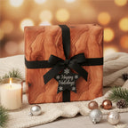 Rustic wood grain Christmas gift wrap with black ribbon and a "Happy Holidays" star tag.