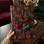 Luxury Christmas wrapping paper with botanical pinecone pattern and burgundy ribbon by Wrapped Studios.