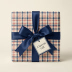 Plaid wrapping paper in red and navy blue with a satin bow on a gift box by Wrapped Studios.