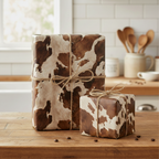 Gifts wrapped in unique brown-and-white cow print wrapping paper with twine bows, perfect for a rustic or western-themed gift.