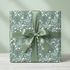 Sage green floral wrapping paper with botanical wildflower pattern and satin ribbon by Wrapped Studios.