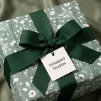 Sage green botanical floral wrapping paper with a dark green ribbon bow by Wrapped Studios.