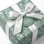Sage green botanical floral wrapping paper with a white satin bow, luxury gift wrap by Wrapped Studios.
