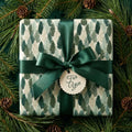 Elegant forest tree Christmas gift wrap with green satin bow and pine branches by Wrapped Studios.