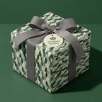 Luxury botanical wrapping paper with green leaf pattern and grey ribbon by Wrapped Studios.