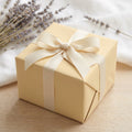 Beige gift box wrapped in solid color wrapping paper with ribbon and bow for birthday, wedding, or party.