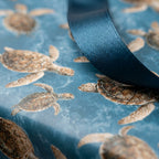Sea turtle wrapping paper with a dark blue satin ribbon, coastal ocean gift wrap by Wrapped Studios.