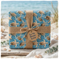 Ocean-themed sea turtle wrapping paper with burlap ribbon on a beach by Wrapped Studios.