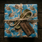 Ocean blue sea turtle wrapping paper by Wrapped Studios, tied with a rustic twine bow.