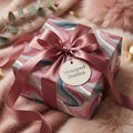 Elegant birthday wrapping paper featuring a pink marble pattern and satin ribbon. Wrapped Studios.