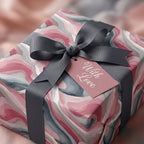 Elegant gift box in abstract pink wrapping paper with gray ribbon and "With Love" tag.