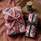 Luxury gift wrap in watercolor-inspired pink and gray marble design with satin and velvet bows.