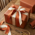 Elegant gift wrapped in solid copper wrapping paper with cream and copper ribbon, rustic wood background.