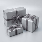 Three sterling silver colored gift boxes with ribbons on a light gray background