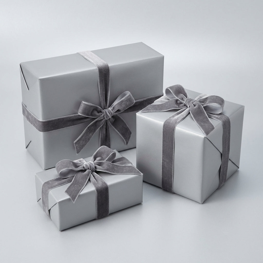 Three sterling silver colored gift boxes with ribbons on a light gray background