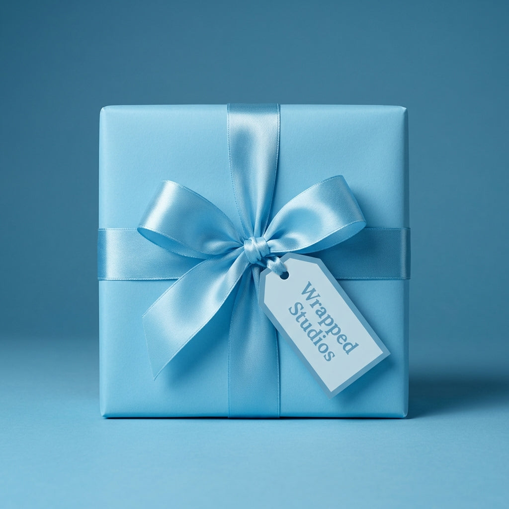 Light blue wrapping paper mockup on a square gift box with satin ribbon and gift tag.