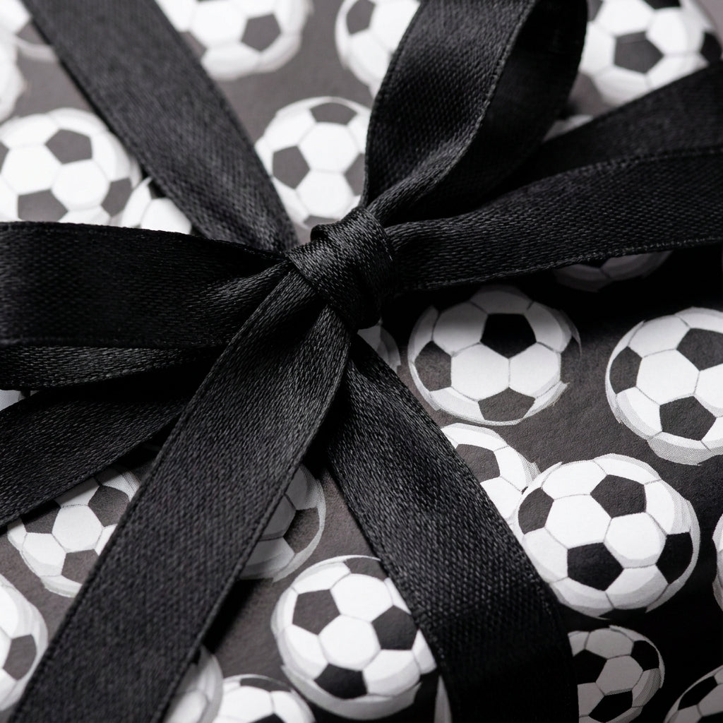 Soccer ball birthday wrapping paper with a black satin bow by Wrapped Studios.