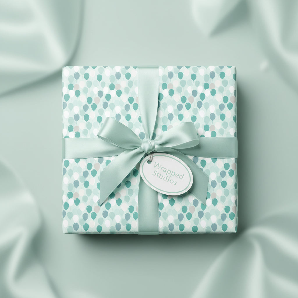 Square gift wrapped in mint balloon birthday wrapping paper with matching ribbon on a draped silky background.