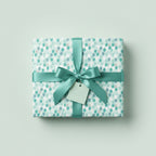 Aqua balloon birthday wrapping paper with satin ribbon and bow on gift box.